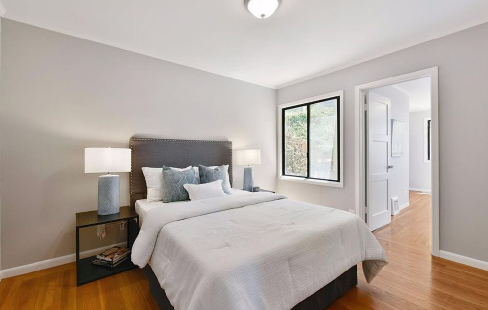 Foto de dormitorio principal actual de tamaño medio sin chimenea con paredes grises y suelo de madera clara