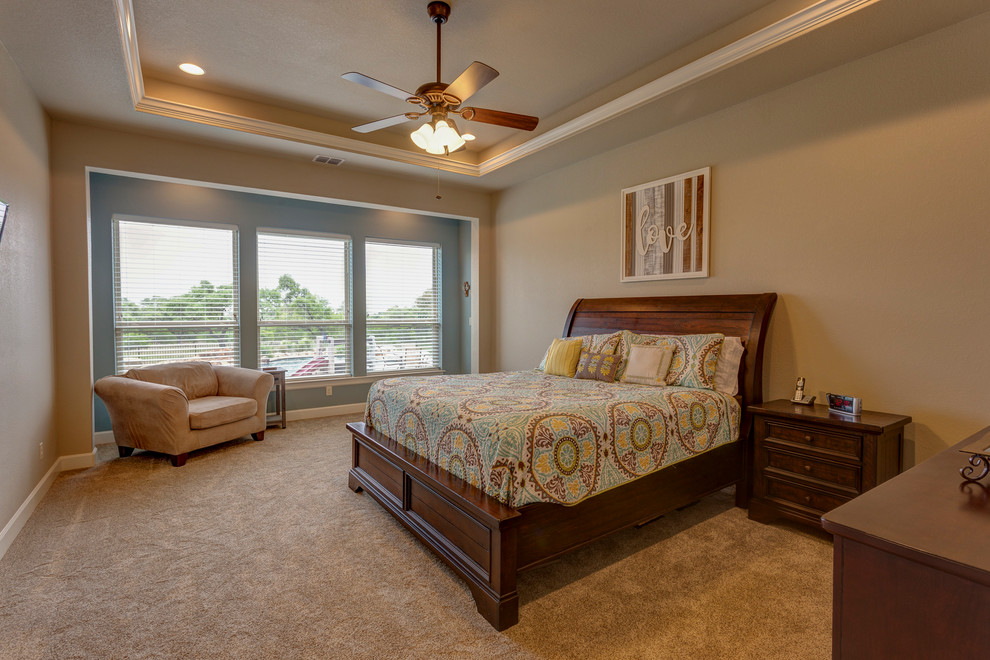 Photo of a large classic master bedroom in Austin with beige walls, carpet, no fireplace and beige floors.