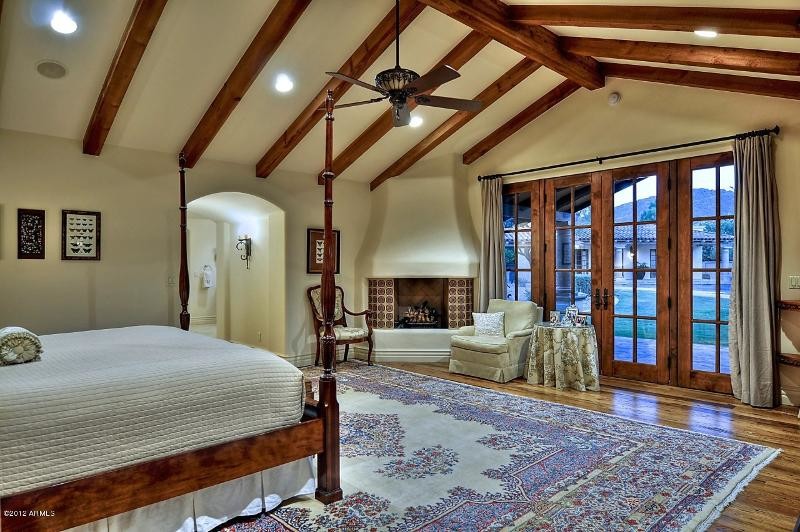 Bedroom - large southwestern master medium tone wood floor bedroom idea in Phoenix with beige walls, a standard fireplace and a tile fireplace