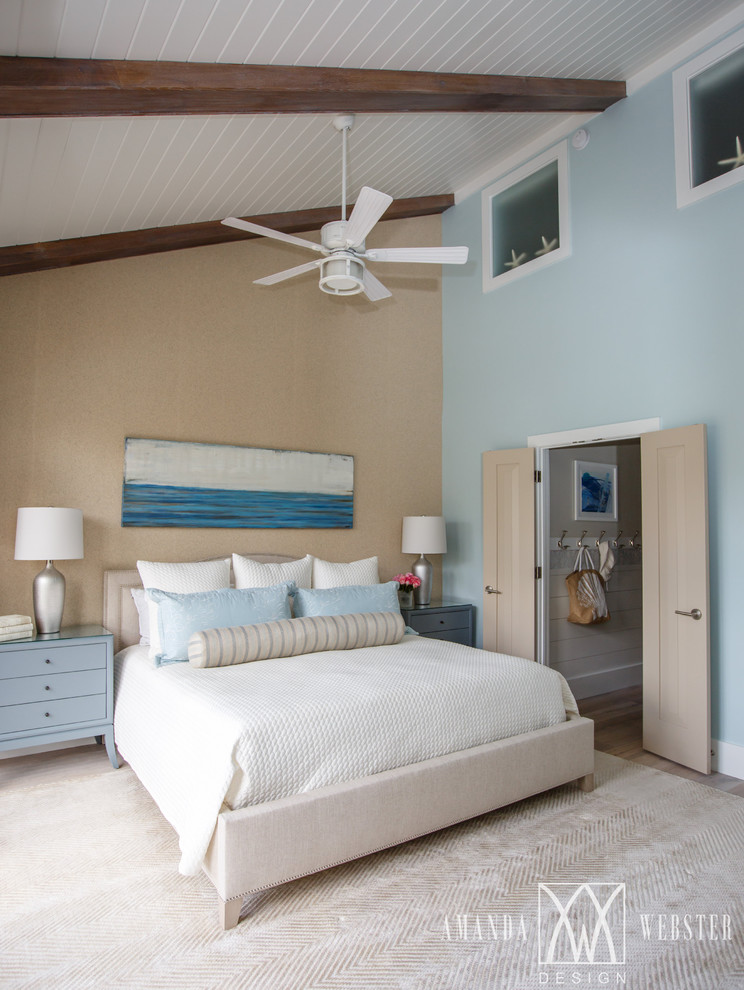 Imagen de dormitorio principal costero sin chimenea con paredes azules y suelo de madera clara