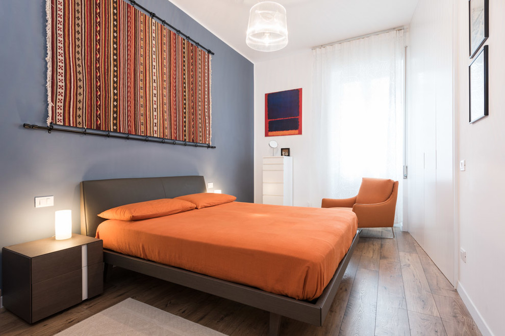 На фото: хозяйская спальня среднего размера в стиле модернизм с синими стенами и светлым паркетным полом с