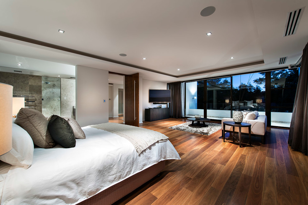 Ejemplo de dormitorio principal actual grande con paredes blancas, suelo de madera en tonos medios y suelo marrón