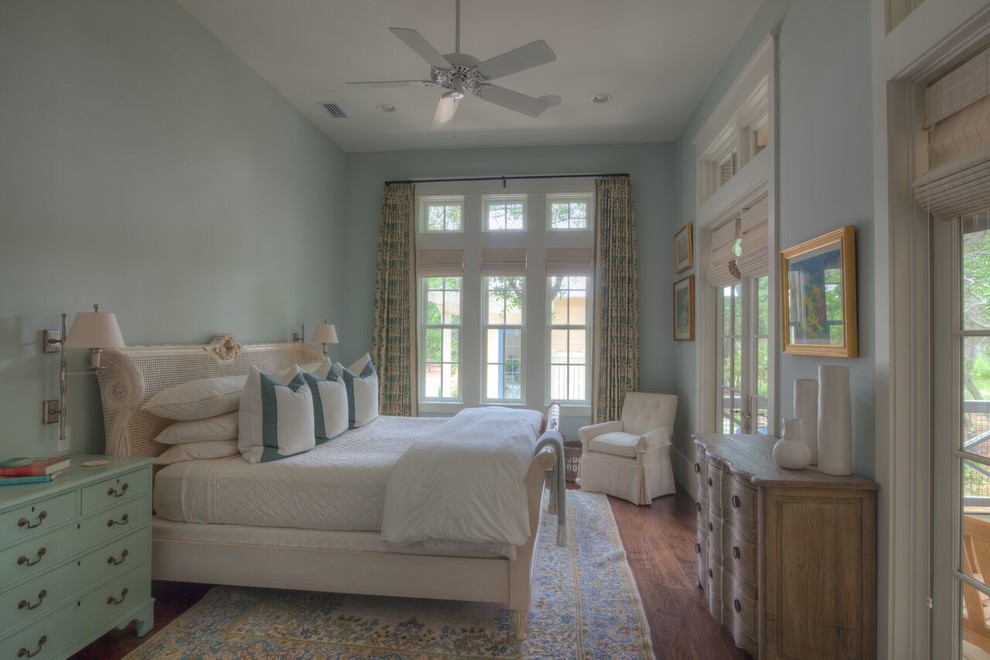 Modelo de habitación de invitados costera de tamaño medio sin chimenea con paredes azules y suelo de madera en tonos medios