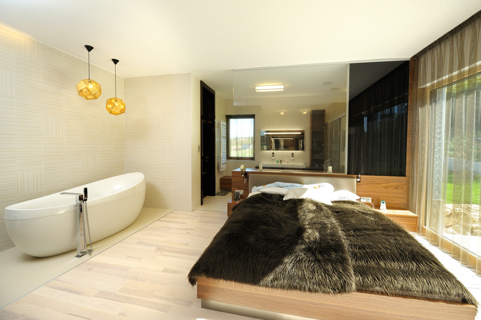 Immagine di una camera da letto contemporanea con pareti beige e parquet chiaro