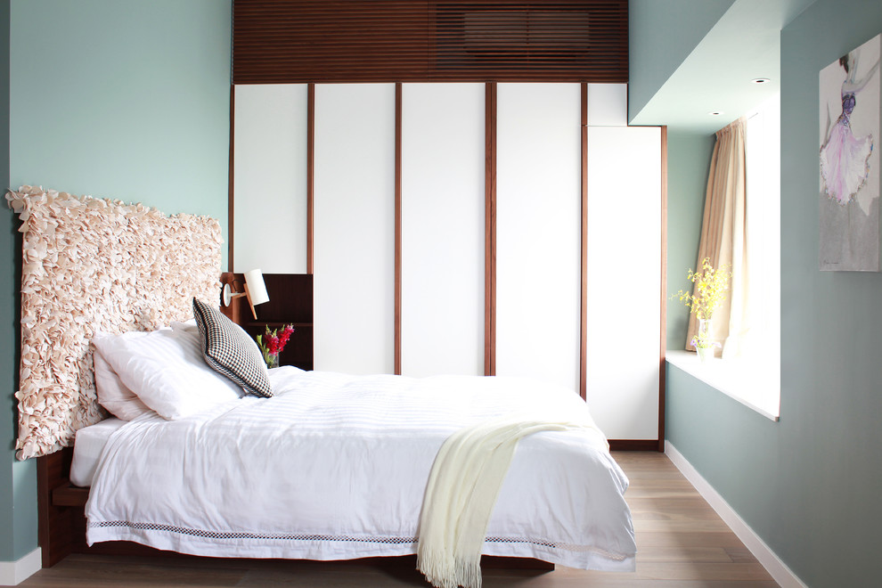 Exempel på ett modernt sovrum, med blå väggar och ljust trägolv
