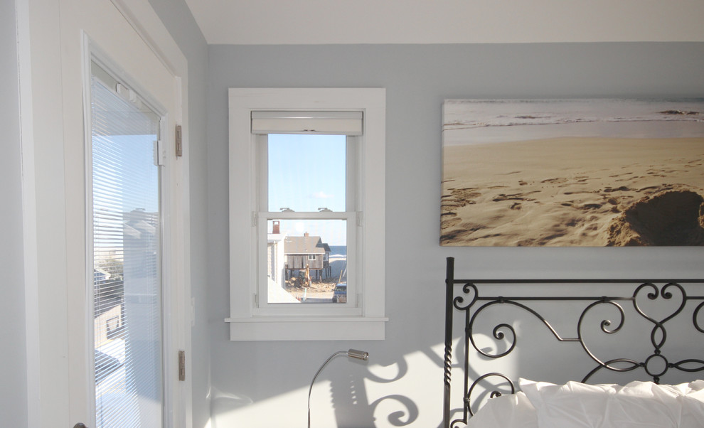 Diseño de dormitorio principal costero con paredes grises y suelo de madera clara