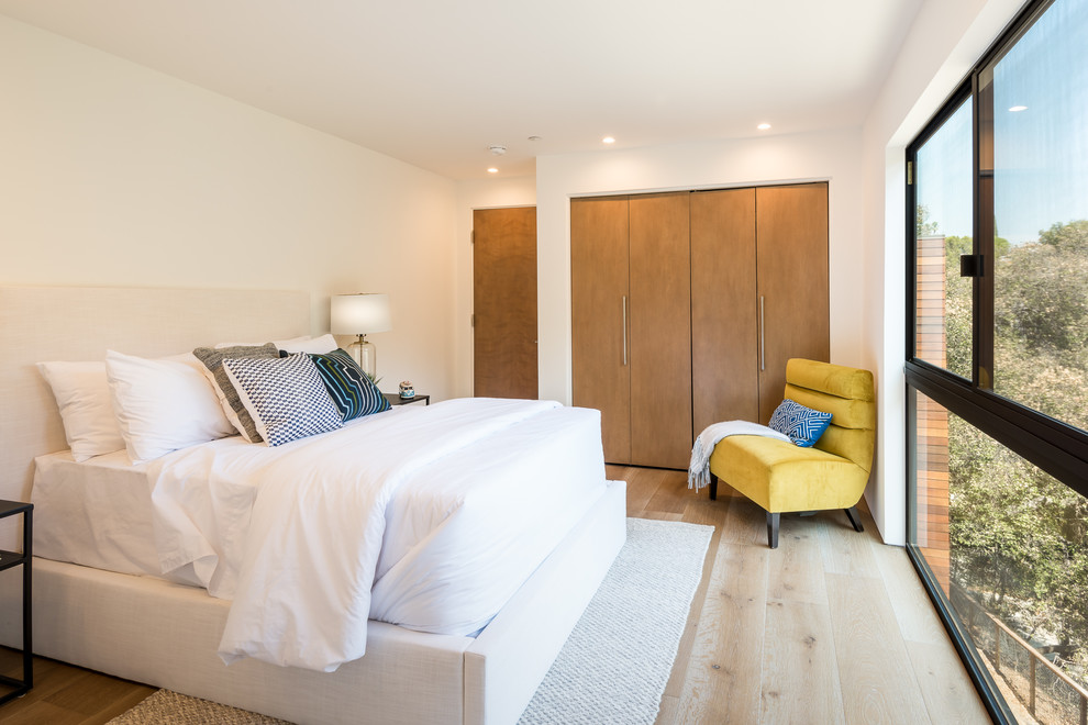 Стильный дизайн: огромная гостевая спальня (комната для гостей) в современном стиле с белыми стенами, паркетным полом среднего тона и коричневым полом - последний тренд