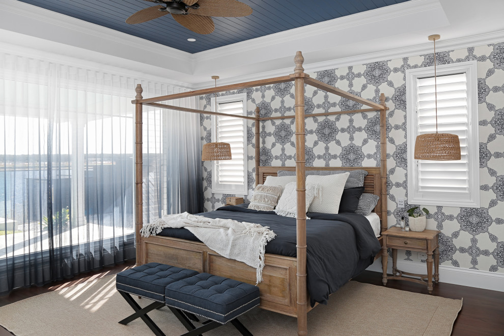 Modelo de dormitorio principal costero grande con paredes multicolor, suelo de madera oscura, suelo marrón, casetón y papel pintado