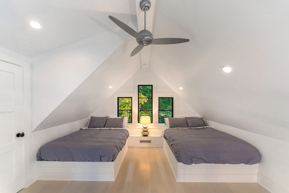 This is an example of a beach style guest bedroom in New York with white walls, light hardwood flooring, no fireplace, beige floors and feature lighting.
