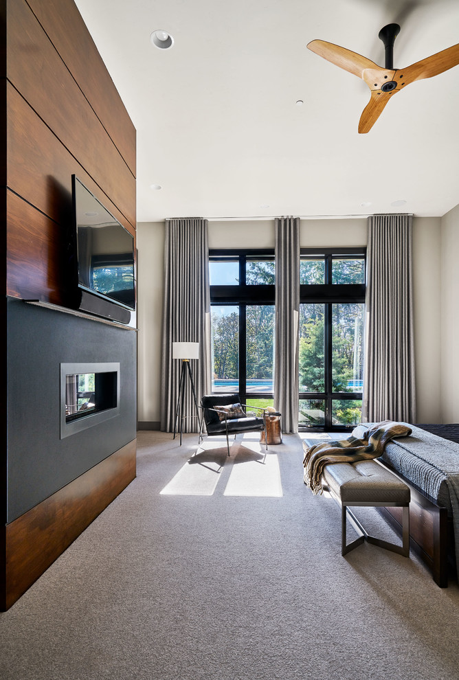 Cette photo montre une grande chambre tendance avec un mur gris, une cheminée standard, un manteau de cheminée en bois et un sol beige.