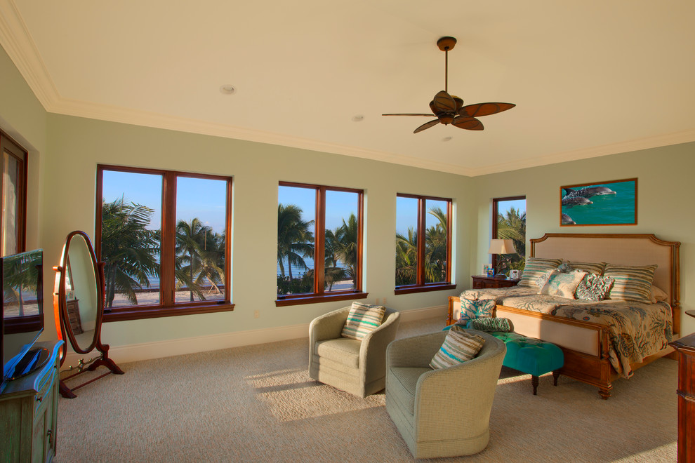 Large world-inspired master bedroom in Miami with green walls, carpet and beige floors.