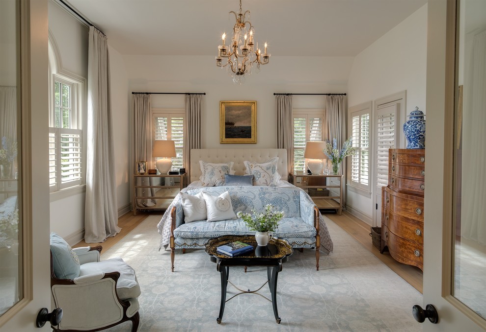 This is an example of a traditional master bedroom in New York with white walls and light hardwood flooring.