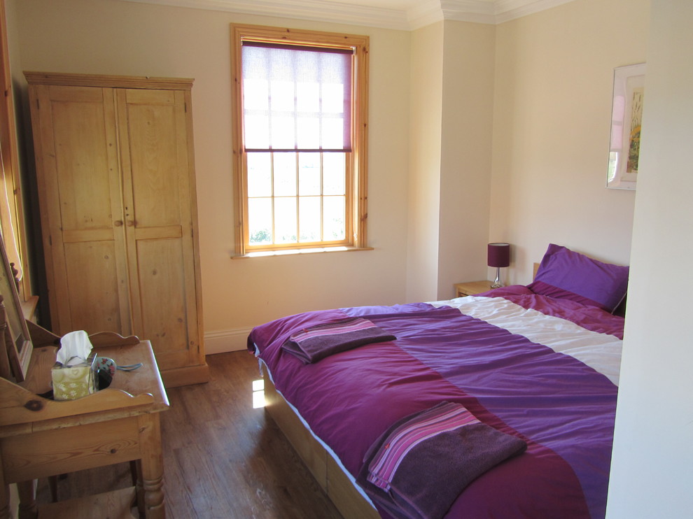 Imagen de habitación de invitados campestre grande sin chimenea con paredes beige y suelo de bambú