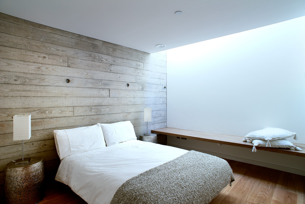 Example of a mid-sized minimalist guest medium tone wood floor bedroom design in Hampshire with white walls and no fireplace