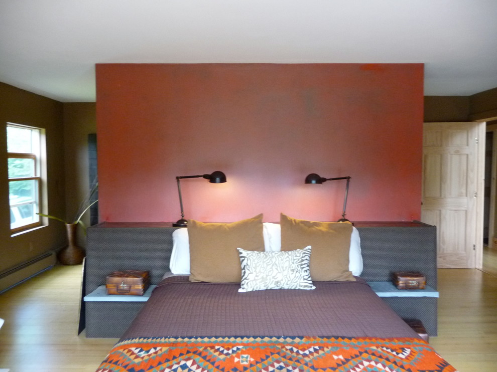 На фото: большая хозяйская спальня в современном стиле с красными стенами, светлым паркетным полом и фасадом камина из камня