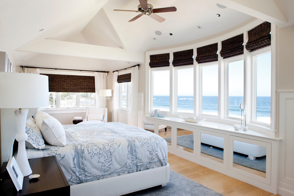Ejemplo de dormitorio principal costero grande sin chimenea con paredes blancas, suelo de madera clara y suelo marrón
