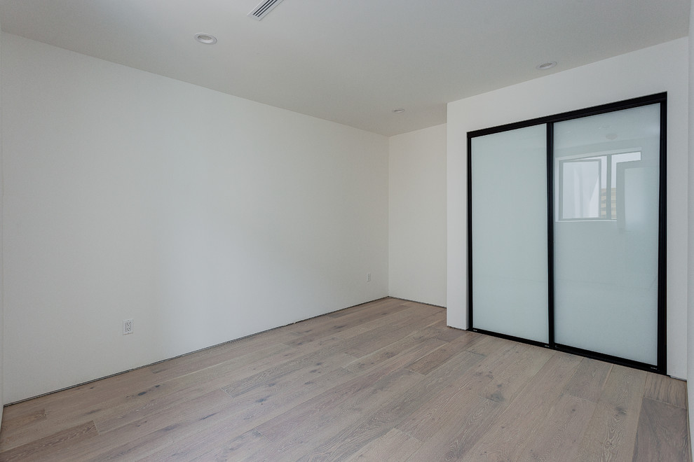 Großes Modernes Hauptschlafzimmer mit weißer Wandfarbe, hellem Holzboden und braunem Boden in Los Angeles