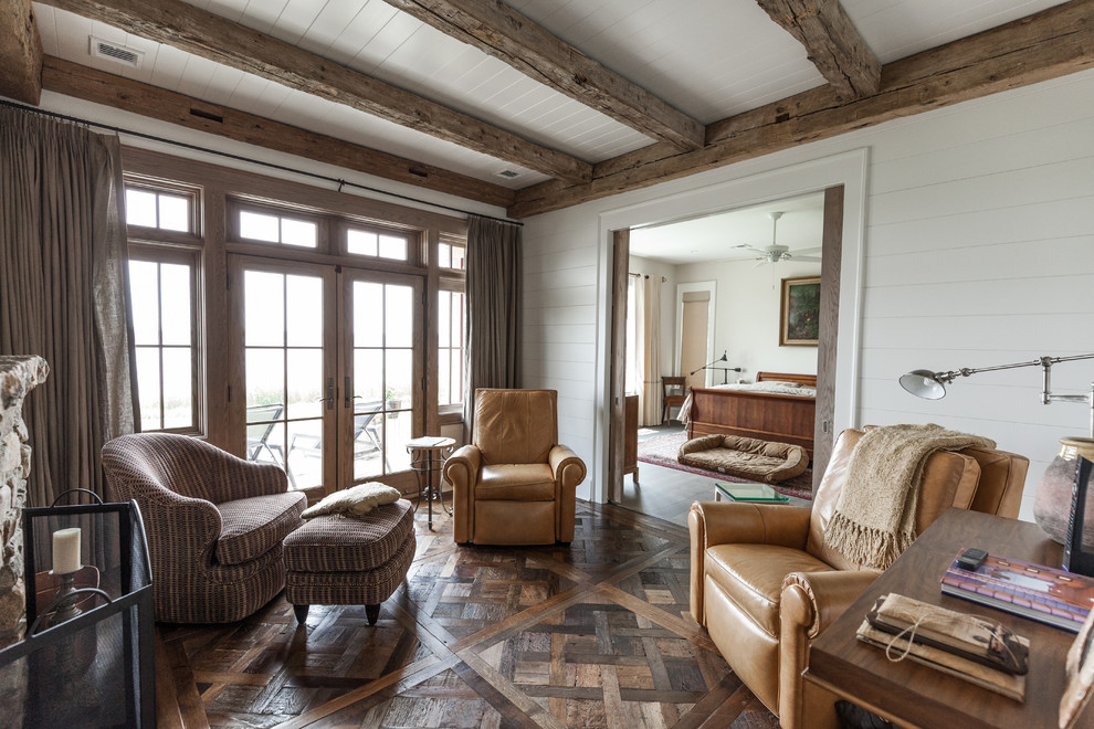 Großes Country Hauptschlafzimmer mit weißer Wandfarbe, braunem Holzboden, Kamin, Kaminumrandung aus Stein und braunem Boden in New York