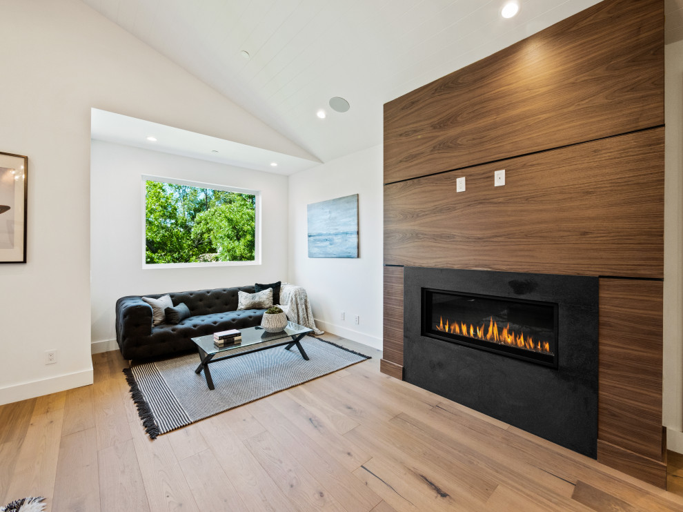 Exemple d'une grande chambre parentale nature avec une cheminée standard, un manteau de cheminée en bois, un plafond voûté et du lambris.