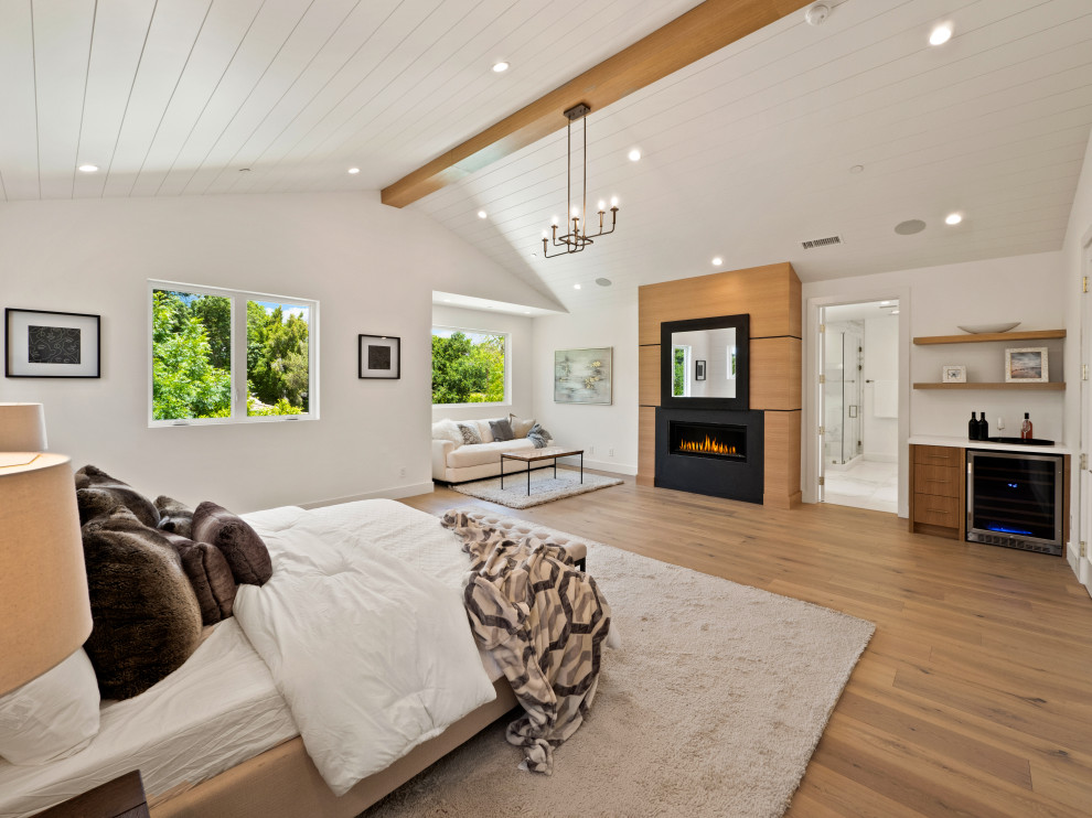 Geräumiges Landhausstil Hauptschlafzimmer mit weißer Wandfarbe, hellem Holzboden, Kamin, verputzter Kaminumrandung, gewölbter Decke und Wandpaneelen in Los Angeles