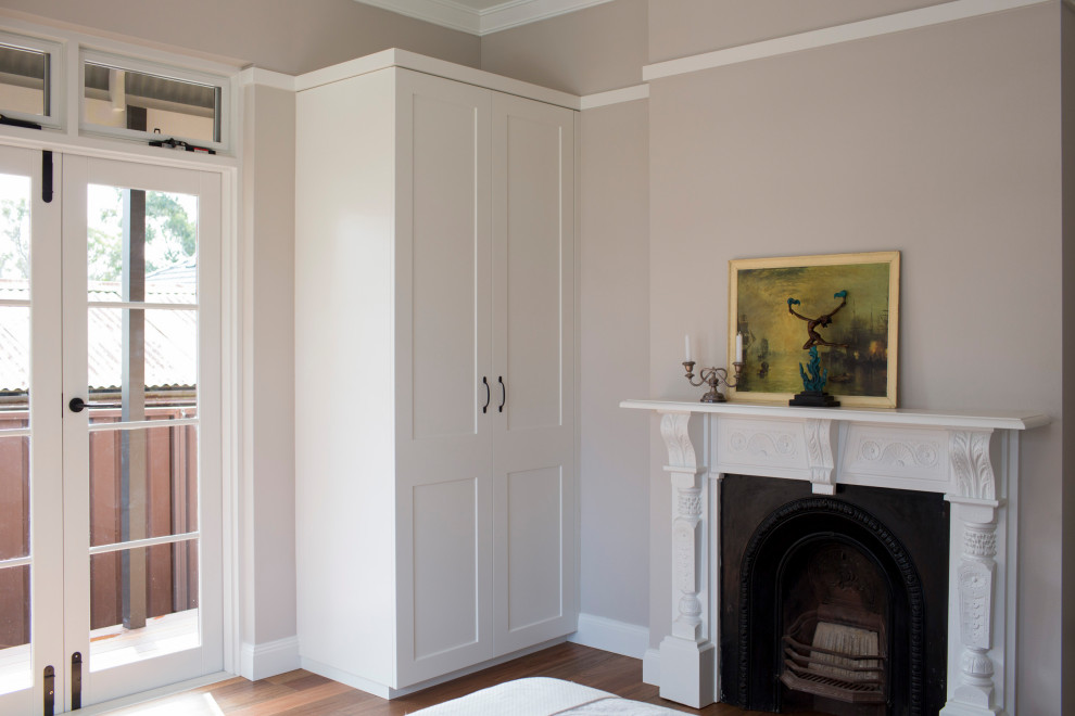 Idées déco pour une chambre d'amis classique de taille moyenne avec un mur beige, parquet foncé, une cheminée standard et un manteau de cheminée en plâtre.