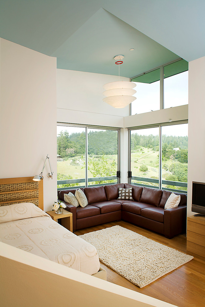 Aménagement d'une chambre contemporaine avec un mur blanc et un sol en bois brun.