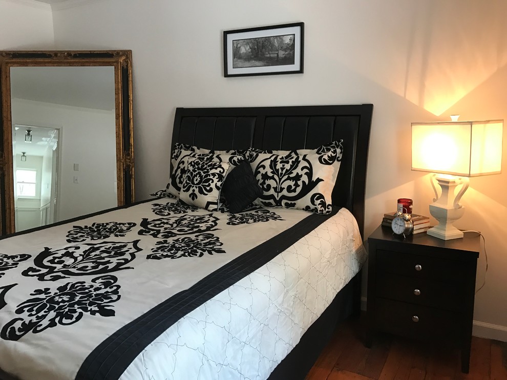 Modelo de habitación de invitados clásica de tamaño medio sin chimenea con paredes blancas y suelo de madera en tonos medios