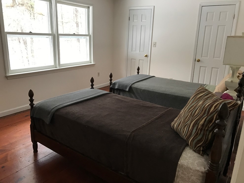 This is an example of a medium sized traditional guest bedroom in New York with white walls, plywood flooring and no fireplace.