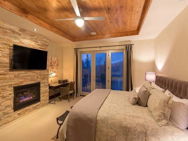 Imagen de dormitorio principal de estilo americano grande con paredes blancas, chimenea lineal y marco de chimenea de piedra