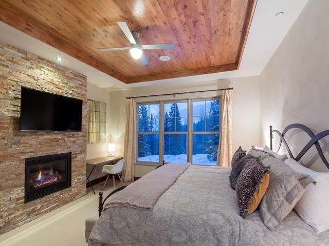 Large classic master bedroom in Indianapolis with white walls, a ribbon fireplace and a stone fireplace surround.