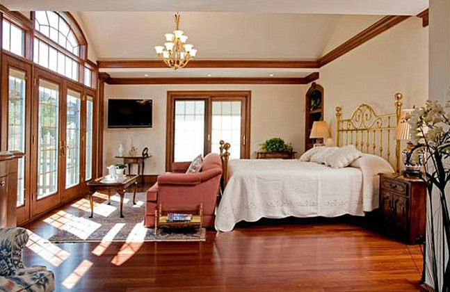 Modelo de dormitorio principal tradicional de tamaño medio con suelo de madera en tonos medios