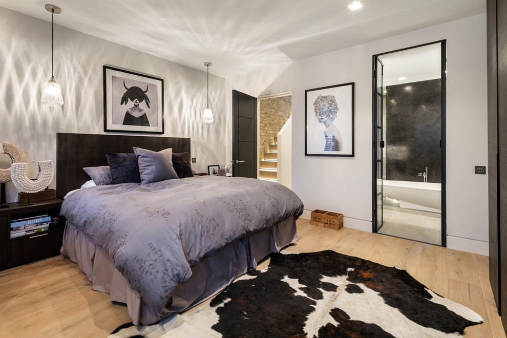 Esempio di una camera da letto industriale di medie dimensioni con pareti bianche, parquet chiaro e pavimento marrone