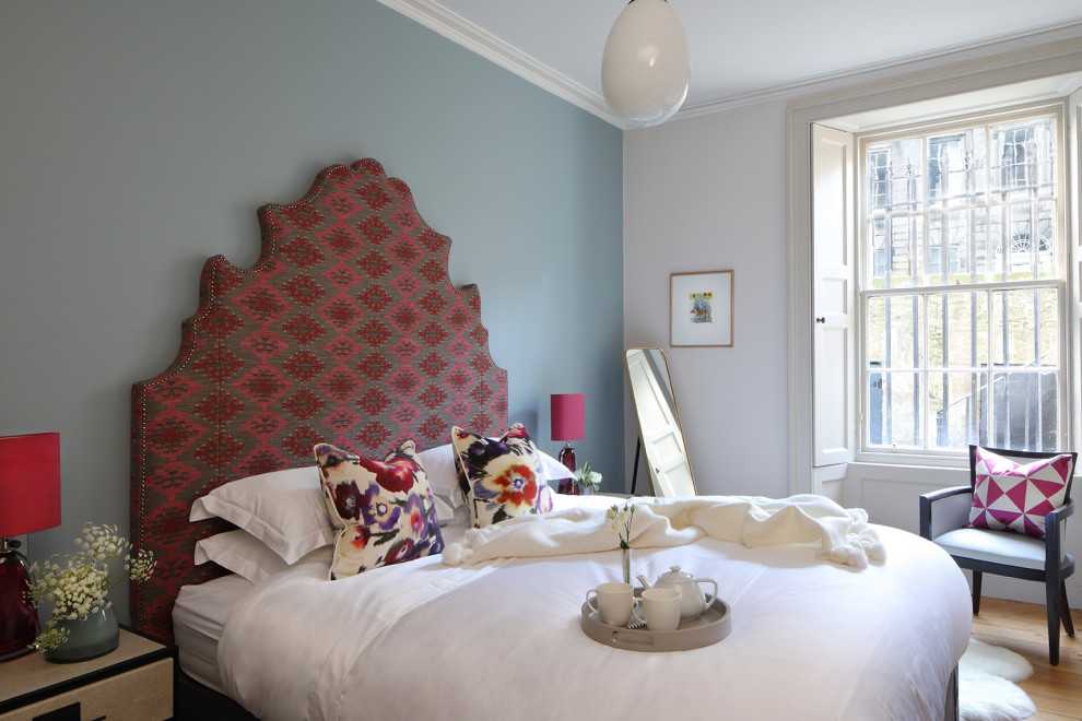 Immagine di una camera da letto tradizionale con pareti blu, pavimento in legno massello medio e pavimento marrone