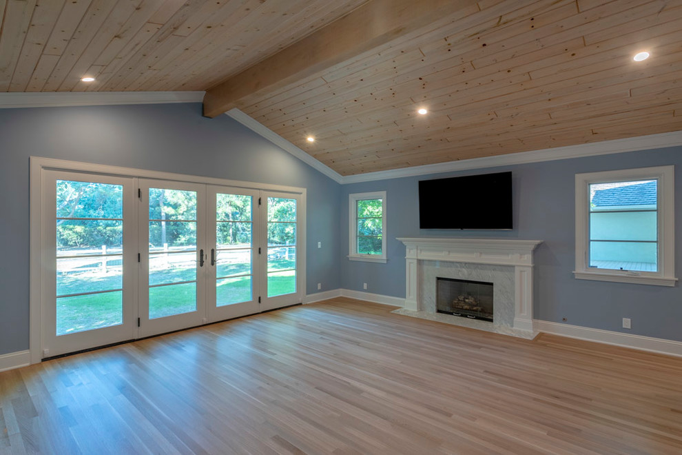 Cette photo montre une très grande chambre parentale chic avec un mur bleu, parquet clair, une cheminée standard et un manteau de cheminée en carrelage.