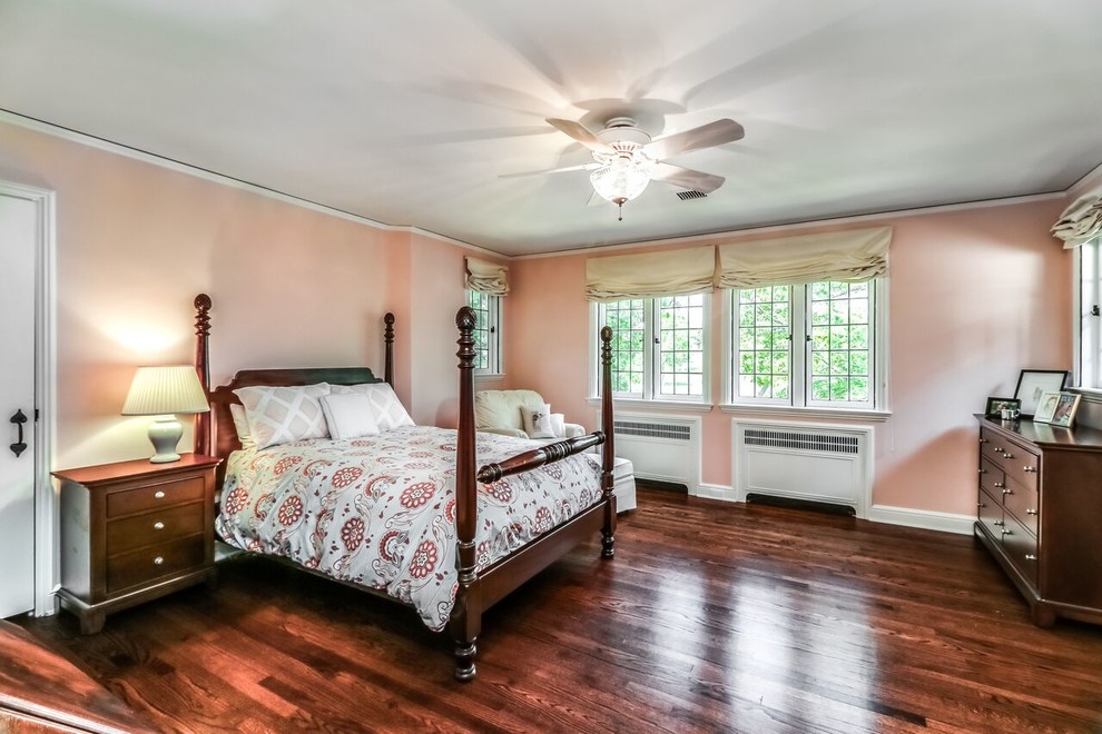 На фото: большая хозяйская спальня в классическом стиле с розовыми стенами, темным паркетным полом и коричневым полом без камина