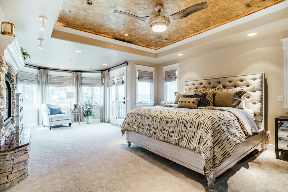 Modelo de dormitorio tradicional renovado con paredes beige, moqueta, todas las chimeneas, marco de chimenea de piedra y suelo beige