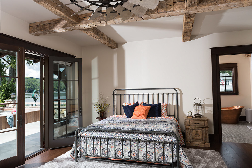 Photo of an expansive rustic master bedroom in New York with white walls and dark hardwood flooring.