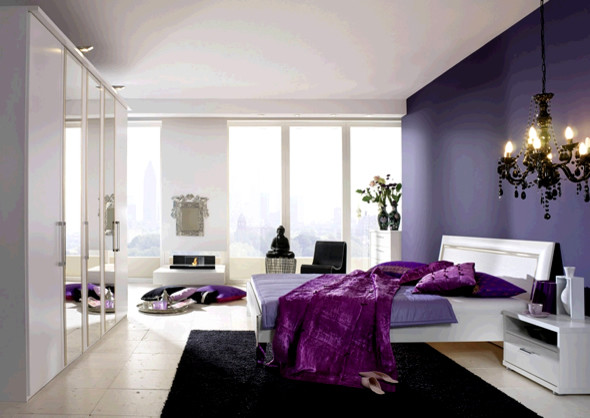 Imagen de dormitorio principal contemporáneo grande con paredes púrpuras, suelo de pizarra, todas las chimeneas y marco de chimenea de piedra