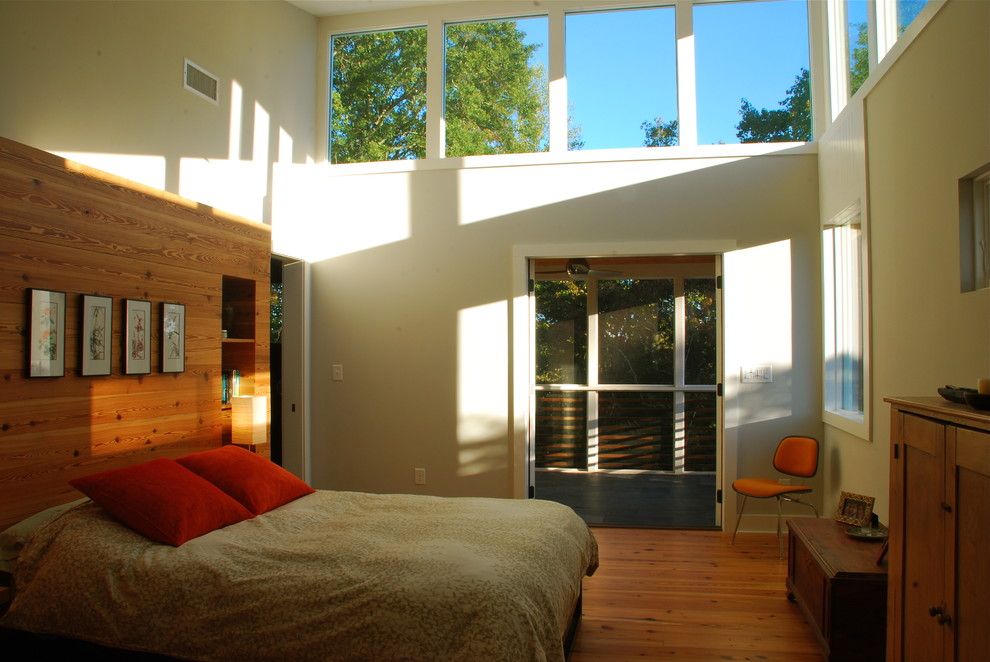 Immagine di una piccola camera matrimoniale minimalista con pareti beige e pavimento in legno massello medio