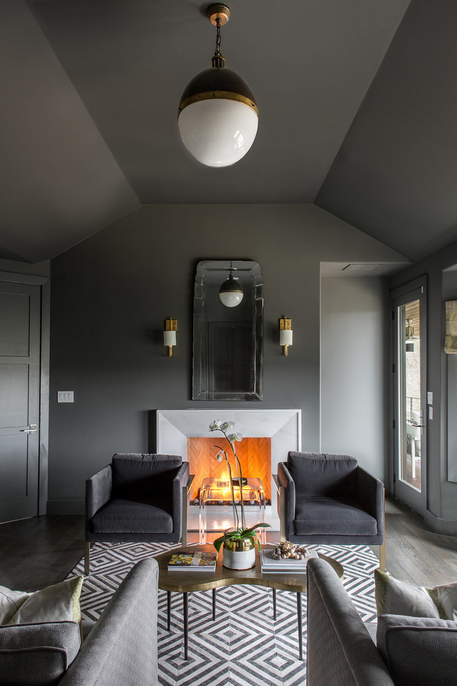 Cette photo montre une chambre tendance avec un mur gris, un sol en bois brun, une cheminée standard, un manteau de cheminée en pierre et un sol gris.