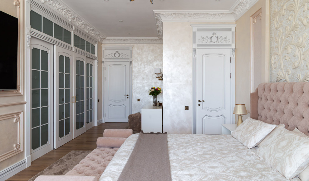 Diseño de dormitorio principal clásico grande con paredes beige, suelo de madera en tonos medios y suelo marrón