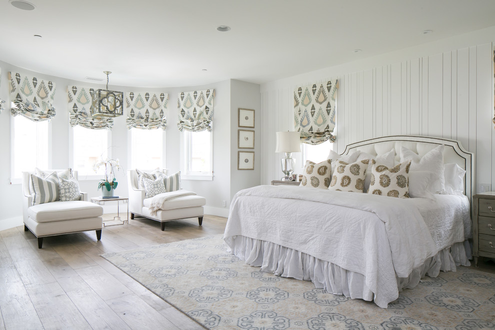 This is an example of a large traditional master bedroom in Orange County with grey walls and light hardwood flooring.