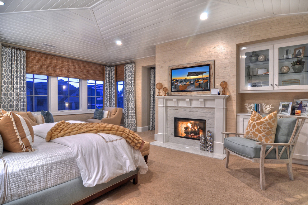 This is an example of a traditional master bedroom in Orange County with beige walls, carpet and a standard fireplace.
