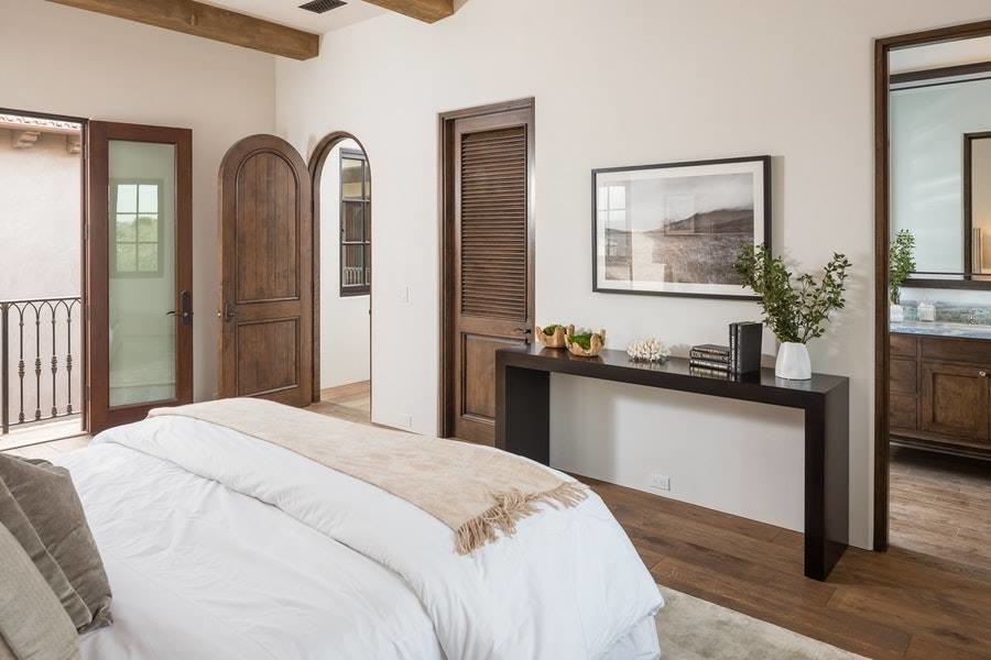 Modelo de dormitorio principal contemporáneo de tamaño medio sin chimenea con paredes blancas, suelo de madera oscura y suelo marrón