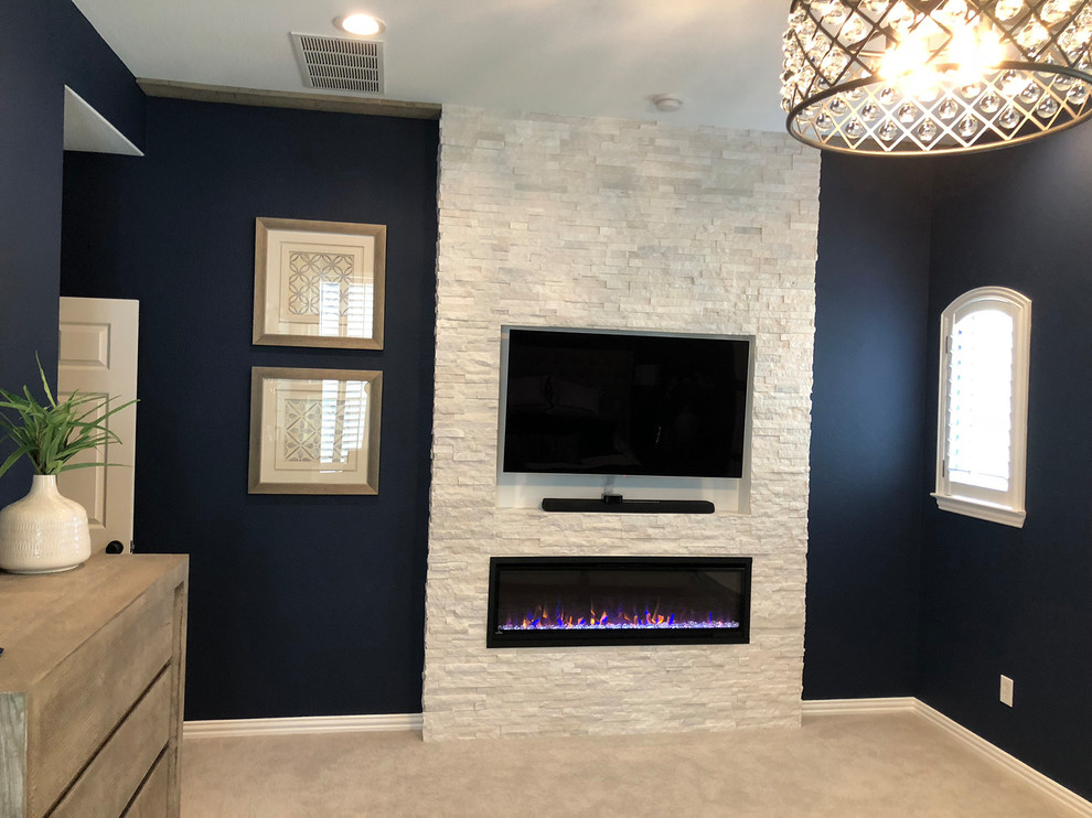 Exemple d'une grande chambre tendance avec un mur bleu, une cheminée standard, un manteau de cheminée en pierre et un sol gris.
