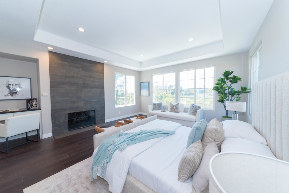 サンフランシスコにある広いコンテンポラリースタイルのおしゃれな主寝室 (グレーの壁、濃色無垢フローリング、標準型暖炉、木材の暖炉まわり、茶色い床、グレーとブラウン) のインテリア