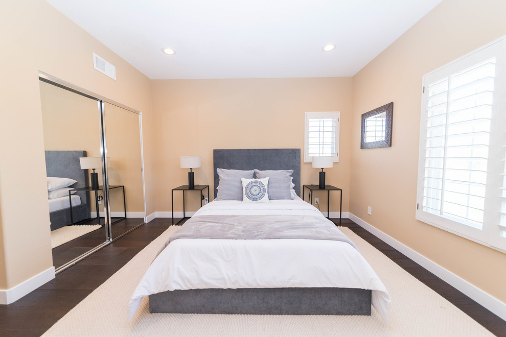На фото: гостевая спальня среднего размера, (комната для гостей) в стиле неоклассика (современная классика) с оранжевыми стенами, темным паркетным полом и коричневым полом без камина с