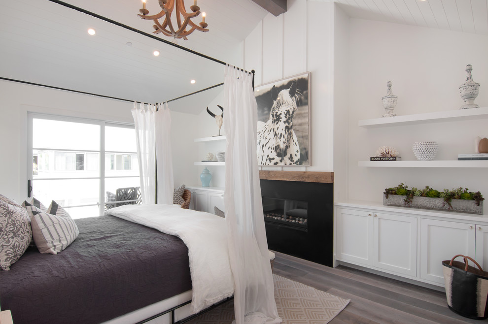 Inspiration for a large coastal master bedroom in Orange County with white walls, a standard fireplace and dark hardwood flooring.