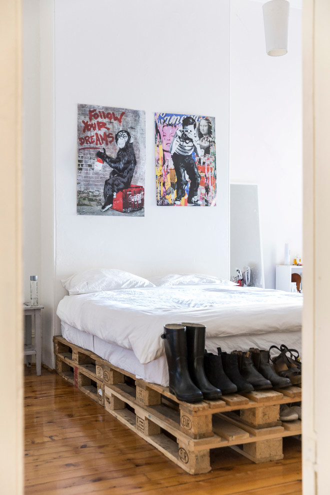 Modelo de dormitorio bohemio con paredes blancas y suelo de madera en tonos medios