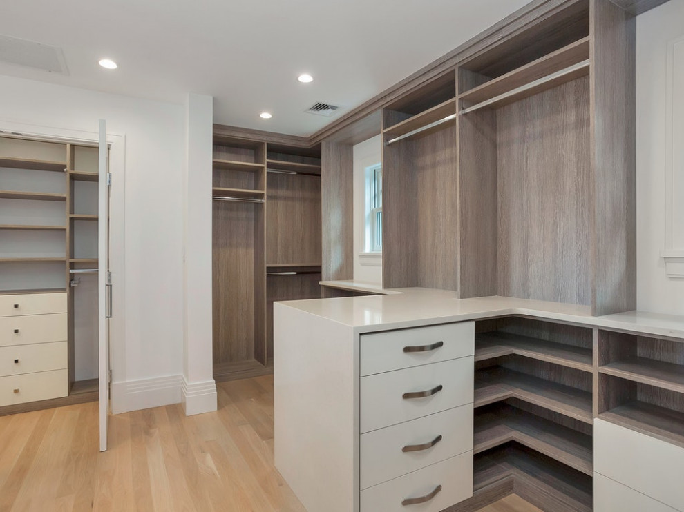 This is an example of an expansive contemporary wardrobe in New York with light hardwood flooring and beige floors.